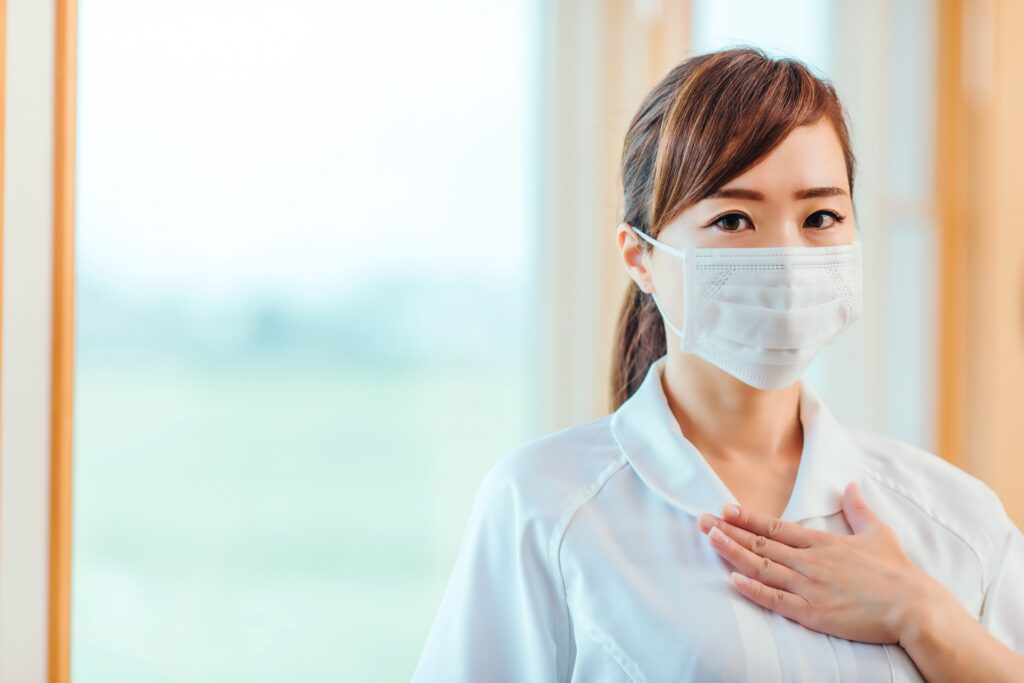 胸に手を当てて利用者に向き合う訪問看護師の穏やかな表情