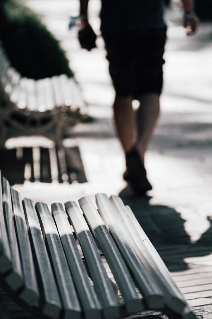 公園のベンチから立ち上がり、歩き出す男性の写真。休息を終えて新たな一歩を踏み出す前向きな気持ちを表している。