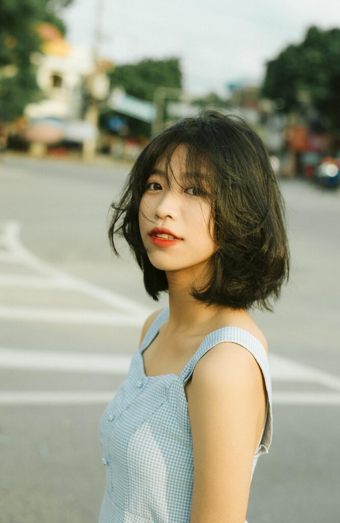 屋外の道を歩きながら振り向いて微笑む女性。自然の中で前向きな気持ちを感じる瞬間。