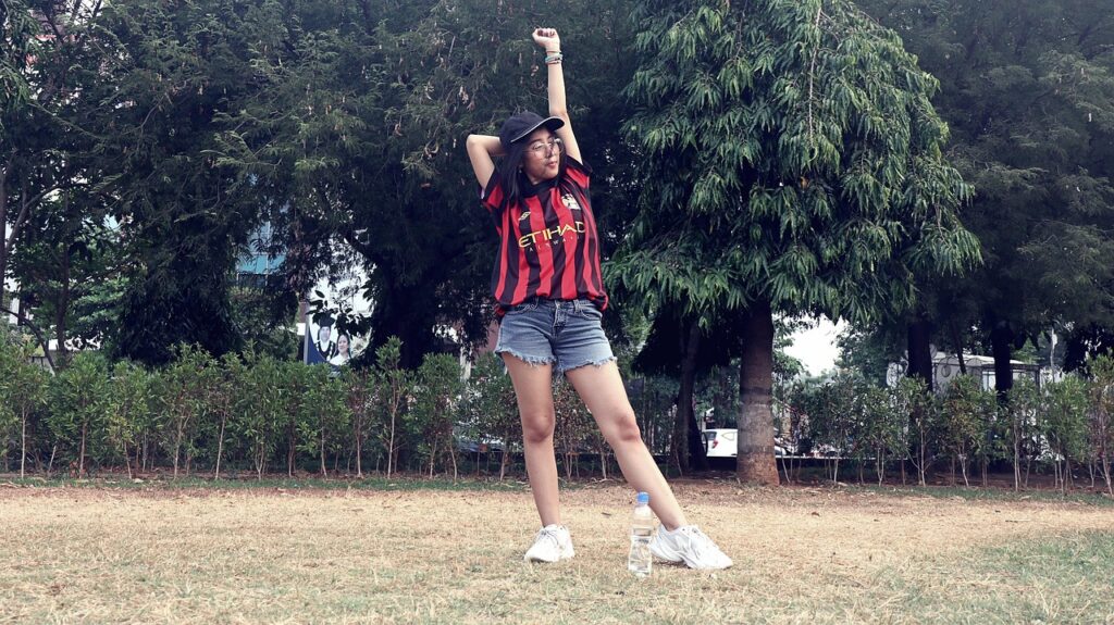 公園で腕を伸ばしてストレッチをする女性。運動前の軽い動きと、気負わない筋トレ習慣を象徴するイメージ。