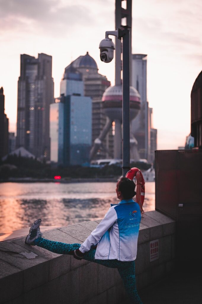 川辺で夕日を背にストレッチする40代女性、日常の中で筋トレを継続する姿勢を象徴