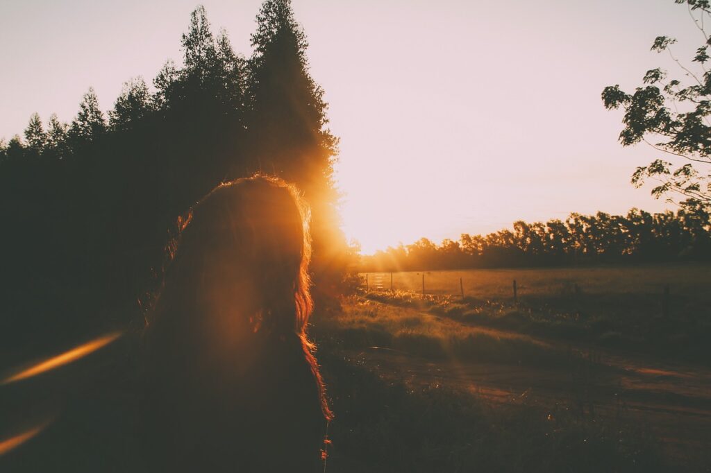 夕日に照らされながら立つ女性のシルエットとオレンジ色の空