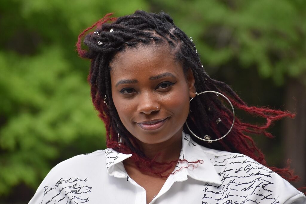 「森を背景に、微笑みながらこちらを見る女性。穏やかな表情が心の安心感を伝える。」