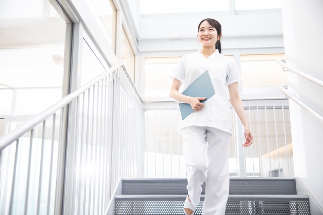 階段を前向きに上がる40代女性看護師のイメージ。キャリアと収入を伸ばす象徴的な写真。