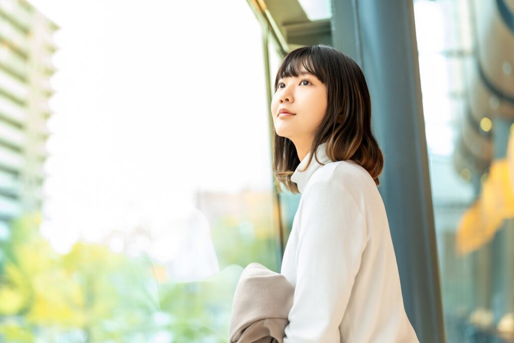 窓の外を眺めながら気持ちを落ち着かせる女性