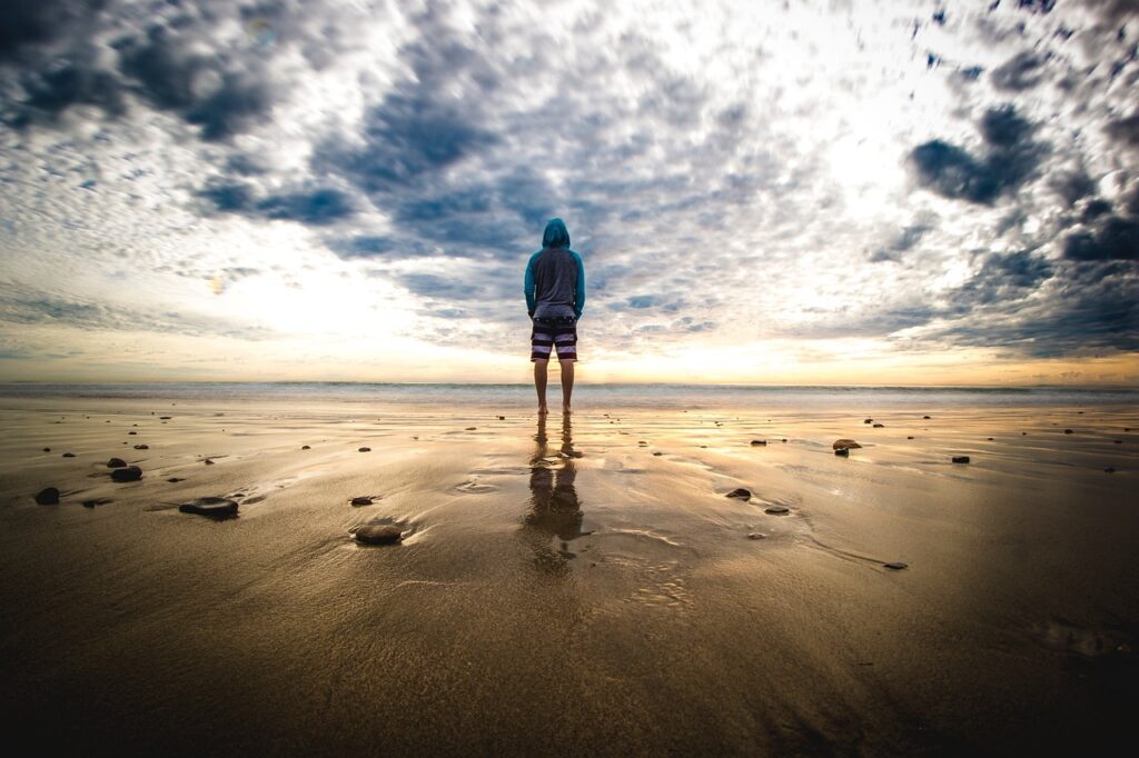 朝の海辺で曇り空を前に一人立ち尽くす人物。
頑張れる人ほど、何も起きていない朝から自分を追い込んでしまう心の状態を象徴している写真。