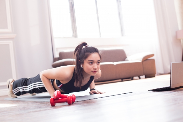 自宅で腕立て伏せを行う女性。初心者向け上半身トレーニングのイメージ