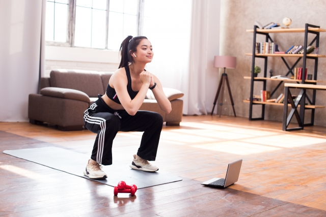 自宅でスクワットを行う女性。初心者向け下半身トレーニングのイメージ