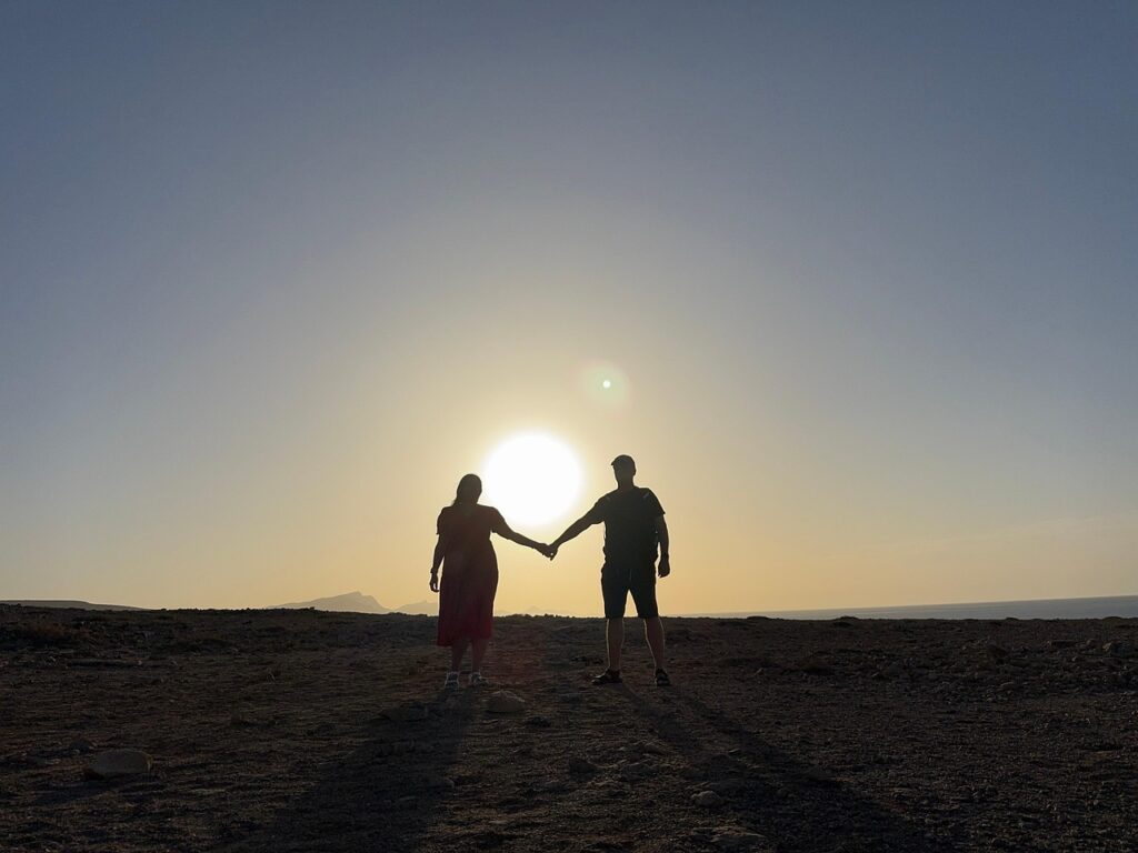 夕日を背に、適度な距離感を保ちながら手をつなぐ二人の後ろ姿。心の境界線が回復し始めた穏やかな関係性を表している。