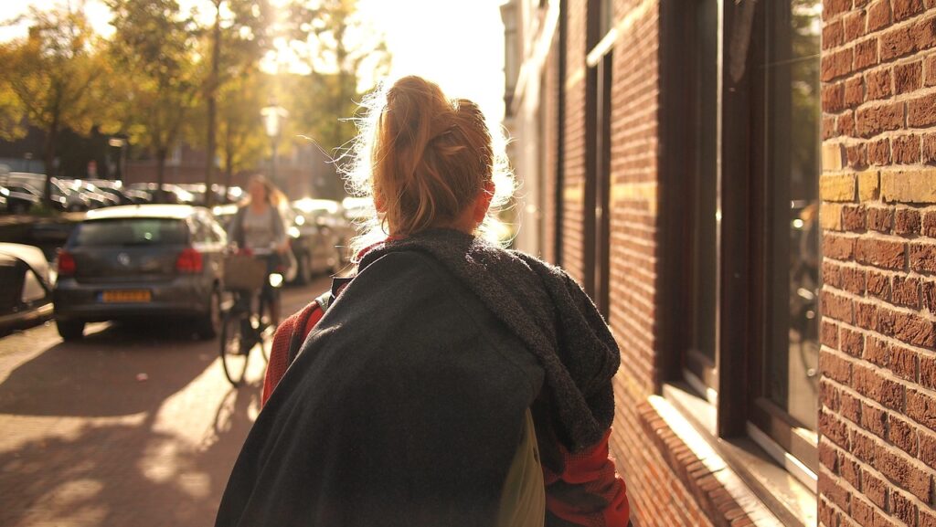 夕方の街を一人で歩く女性の後ろ姿。小さな一歩を踏み出すイメージ