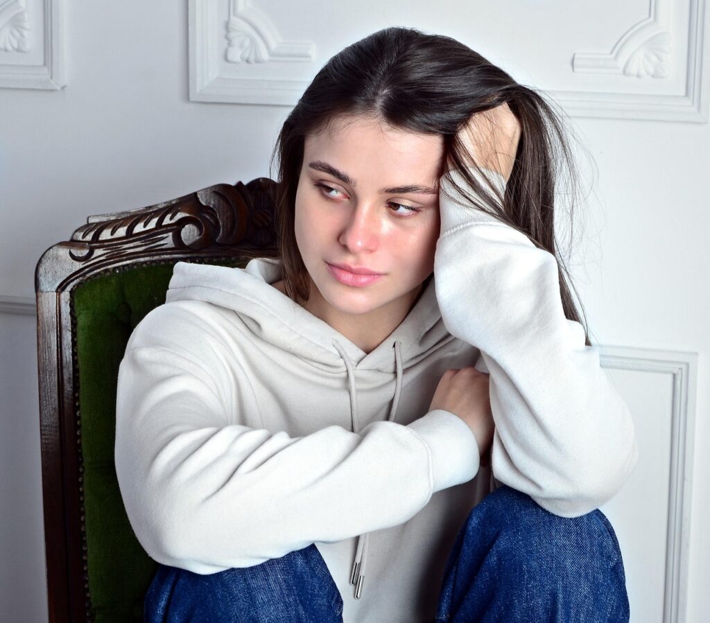 ひとり椅子に座り、感情を抱え込むようにうつむく女性。我慢を重ねてきた人に、遅れて訪れる涙の前触れを表している。