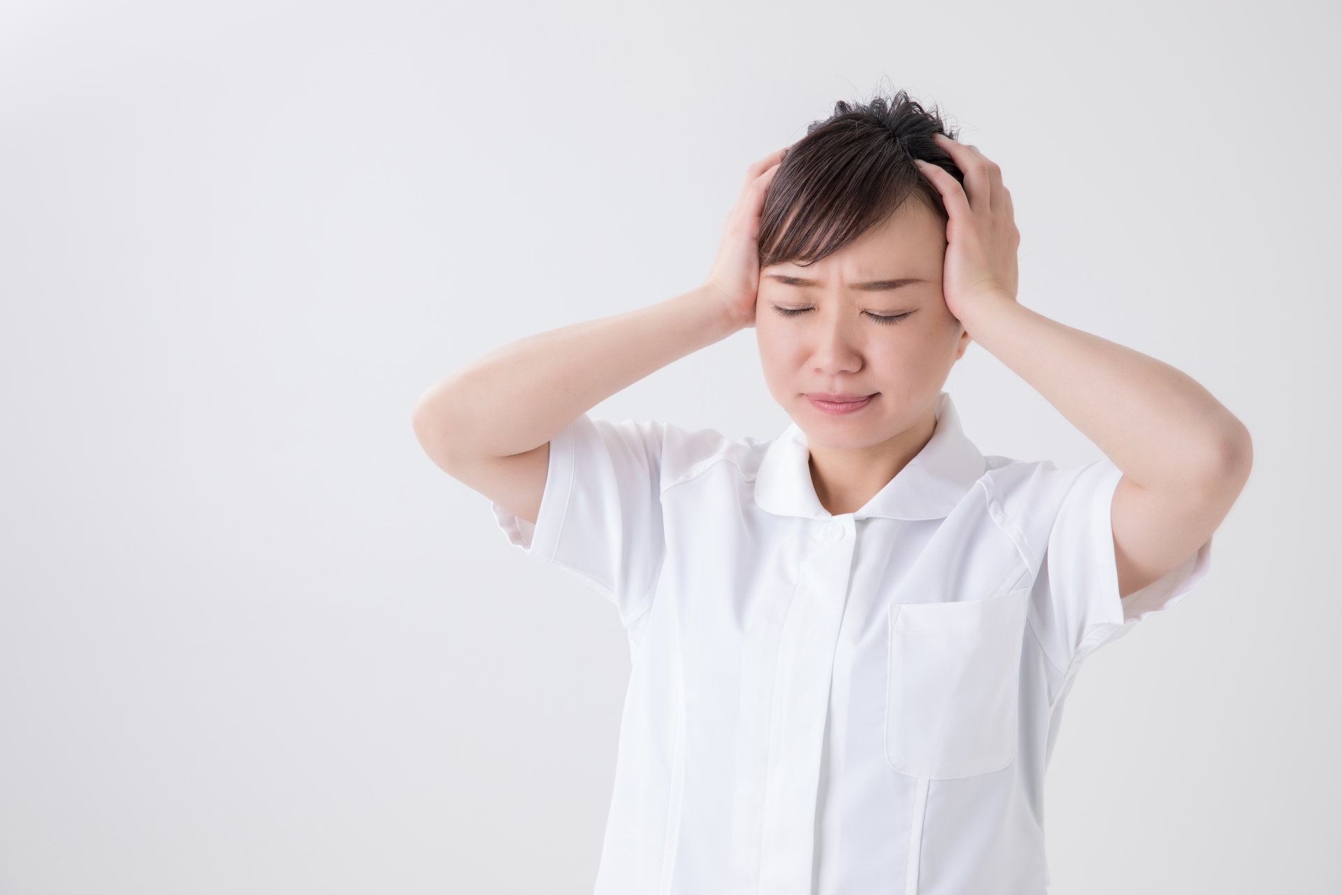 頭を抱えて疲労やストレスを感じている40代看護師のイメージ