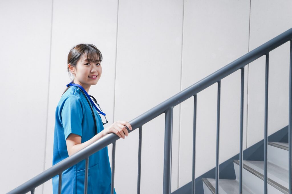 階段を上りながら運動習慣を取り入れる看護師の女性