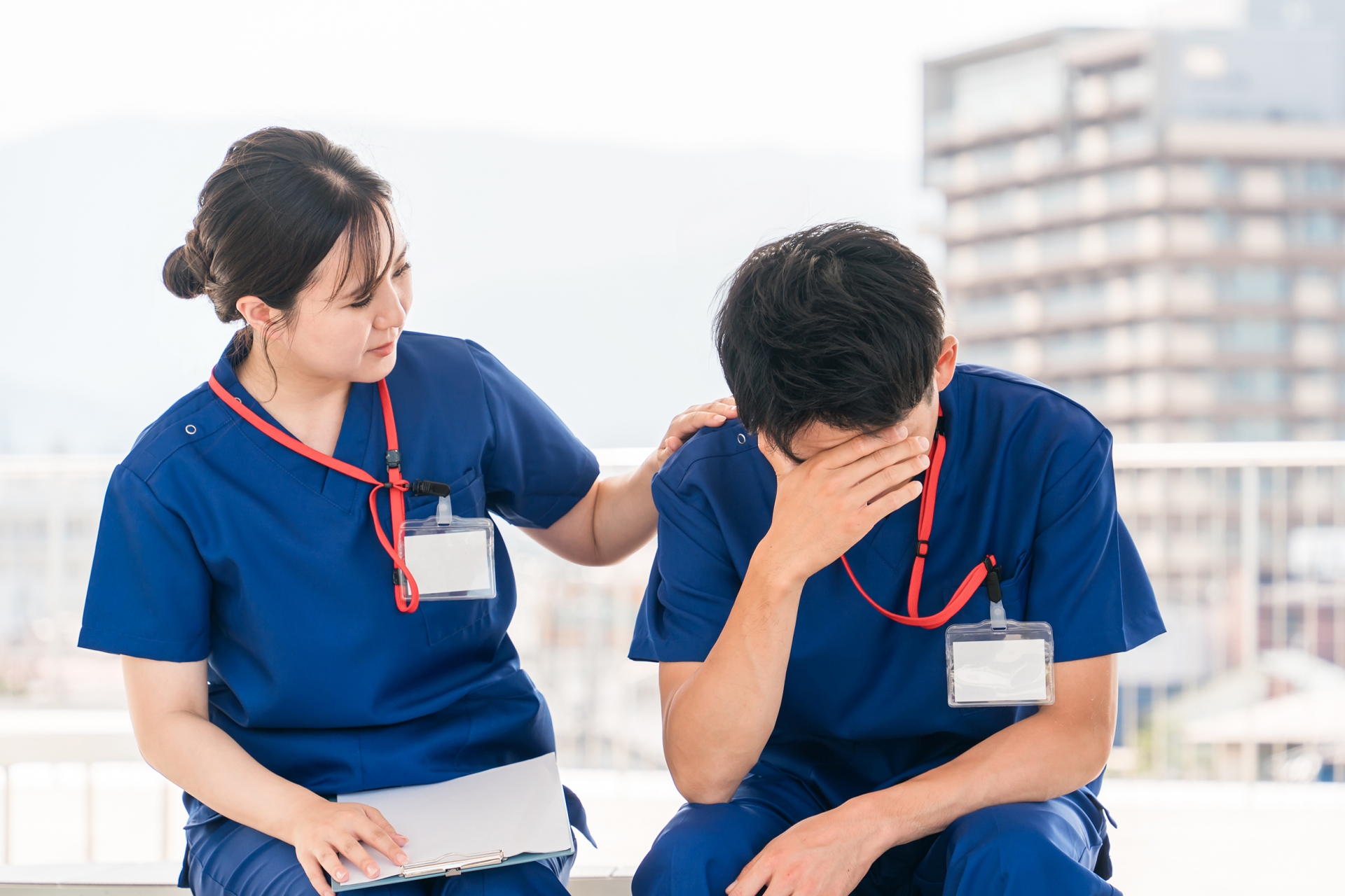 職場で落ち込む男性看護師の肩に手を添える女性看護師の様子