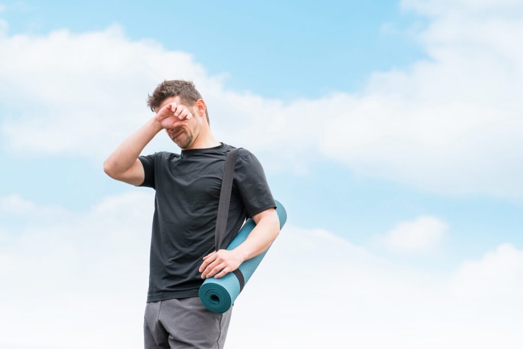 運動する気力が出ず、ヨガマットを持ったまま疲れた様子の男性