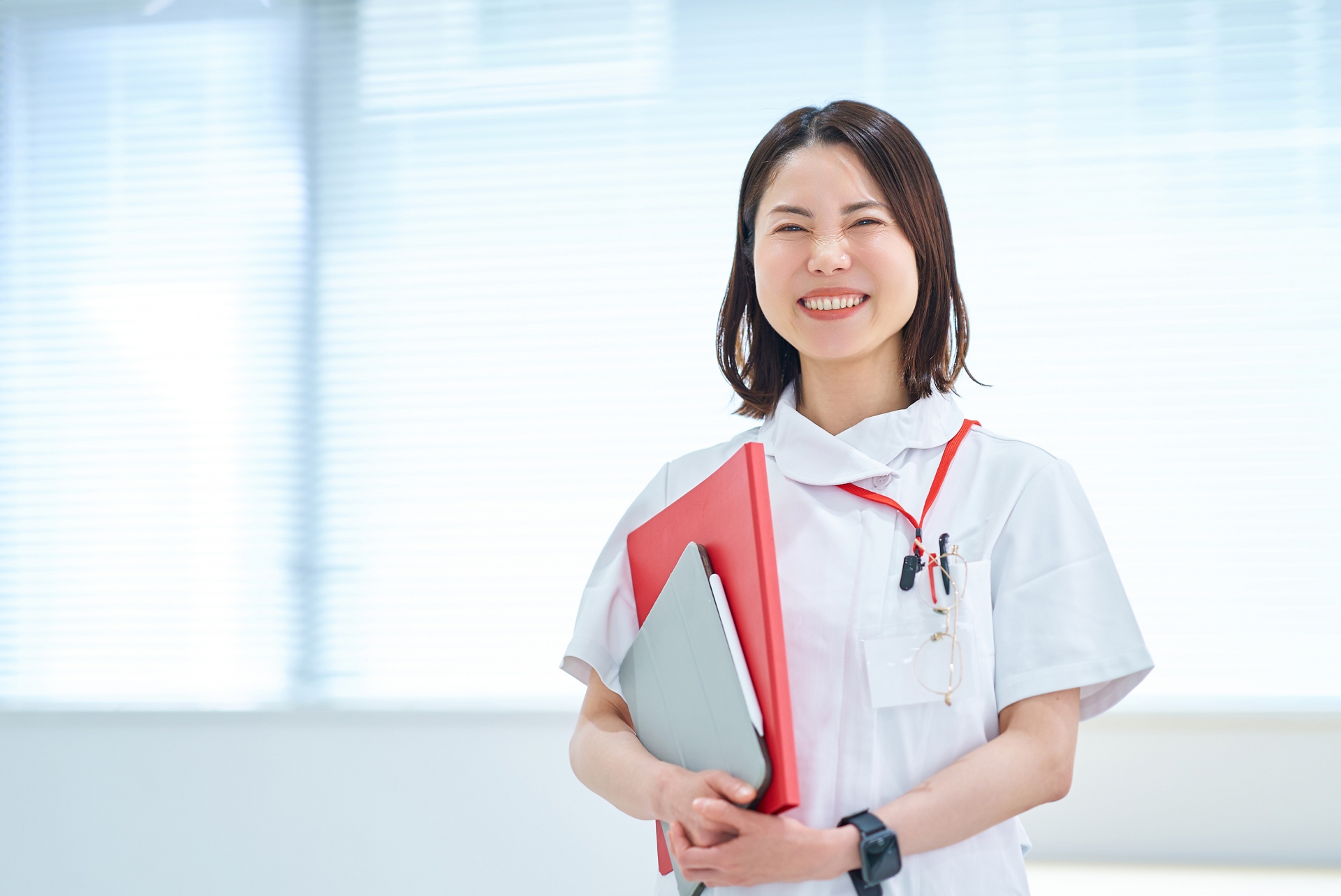 笑顔で書類を抱える40代女性看護師。夜勤と向き合いながら健康的に働くイメージ