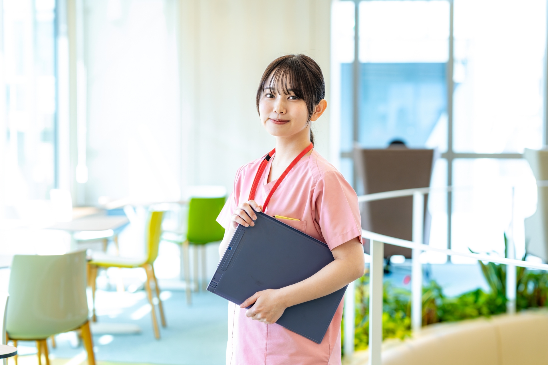 訪問看護ステーションでファイルを持ちながら微笑む女性看護師