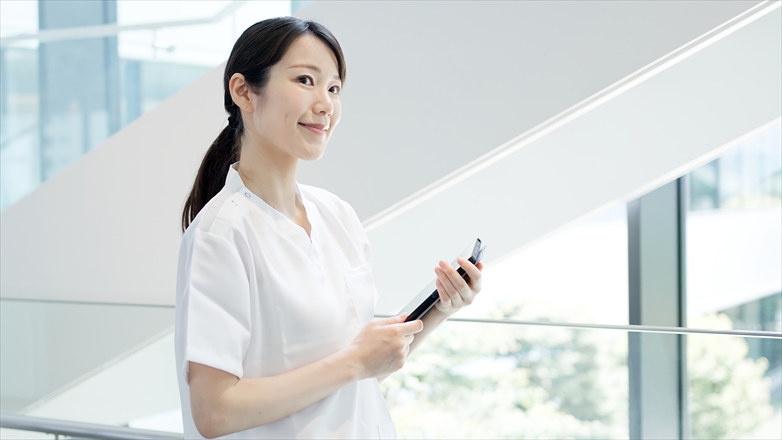 明るい院内でタブレットを持つ女性看護師